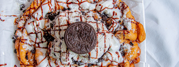 Funnel cake with whip cream and an oreo on top