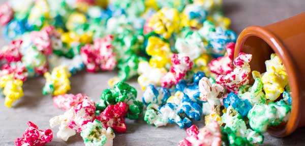 blue yellow red and green colored popcorn poured out on tabletop